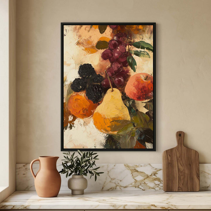 A framed vertical art print depicting a still life of fruit, including a pear, grapes, and an orange, displayed on a beige wall above a marble-topped surface with a terracotta pitcher, a small potted plant, and a wooden cutting board.