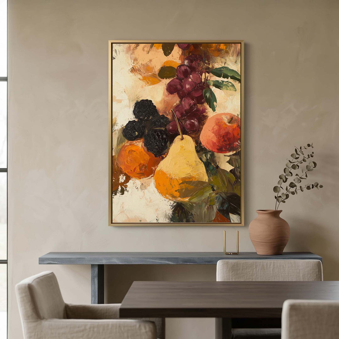 A framed still life painting of fruit hangs on a beige wall above a dining table and chairs, with a vase of dried branches to the right.